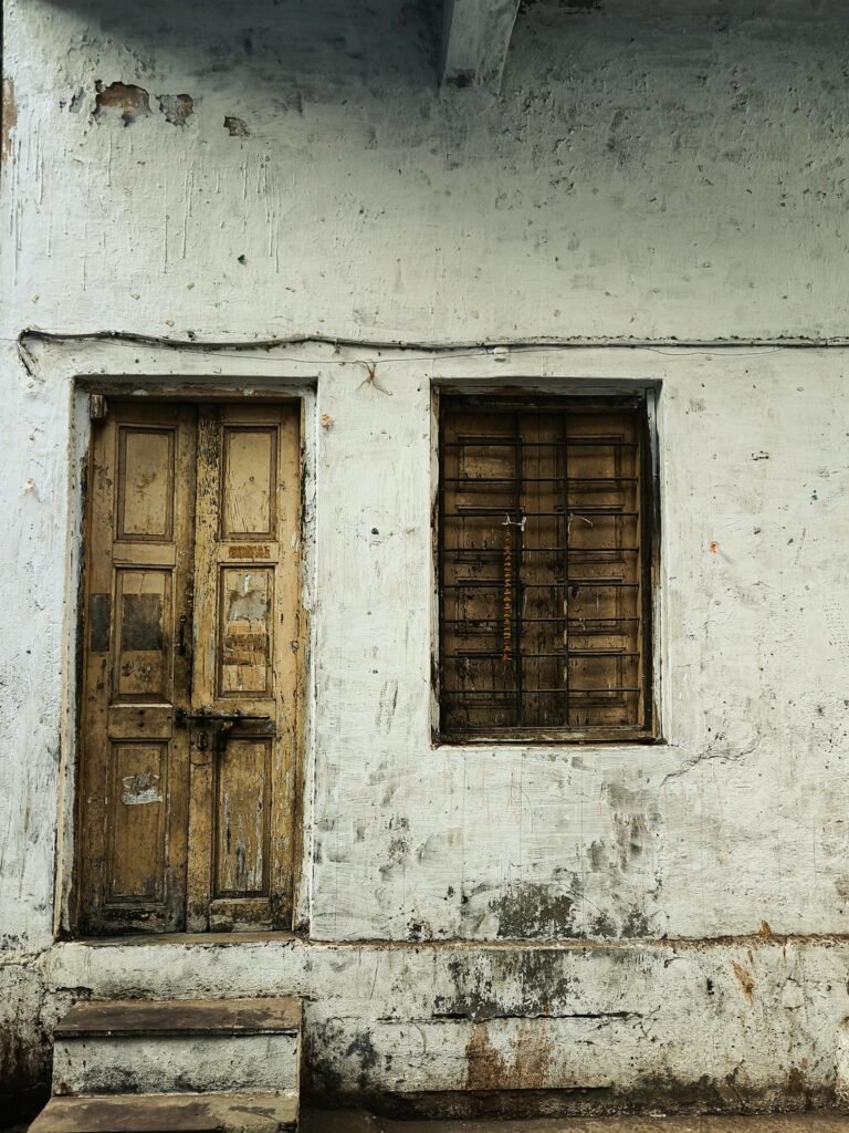 A weathered wooden door and window on an old building facade in Ahmedabad, India.